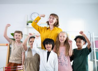 Portrait of a teacher and kids in a classroom where children have pleasure learning.